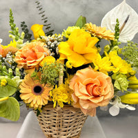 Close-up of Golden Elegance flower basket with fresh peach roses, yellow flowers, orchids and seasonal foliage